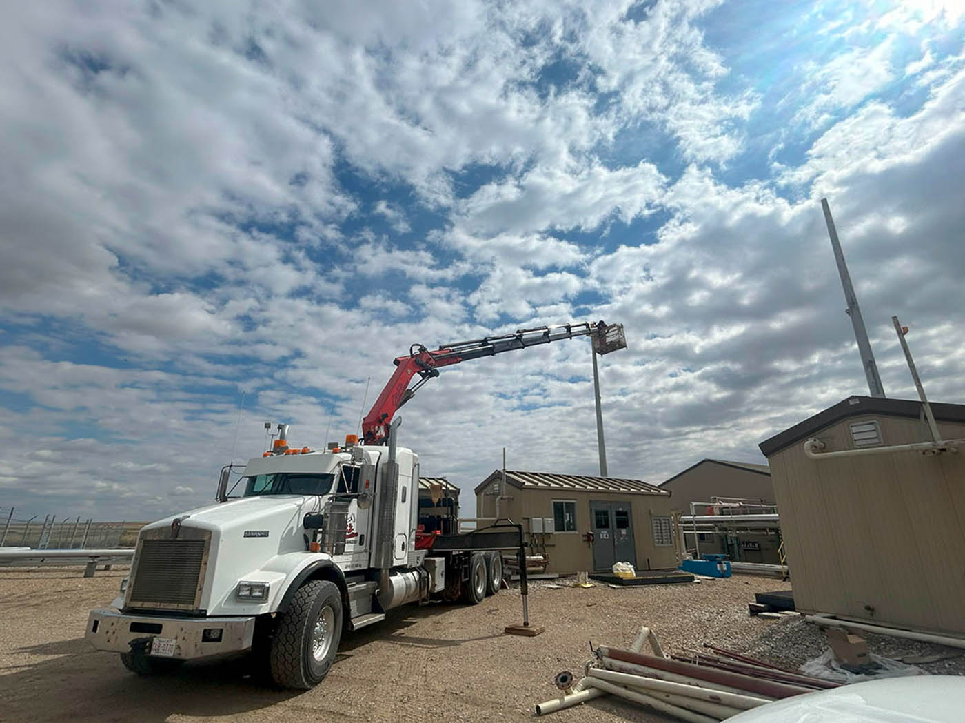 A truck lifts a small portable toilet onto a flatbed, showcasing the process of transporting sanitation equipment.